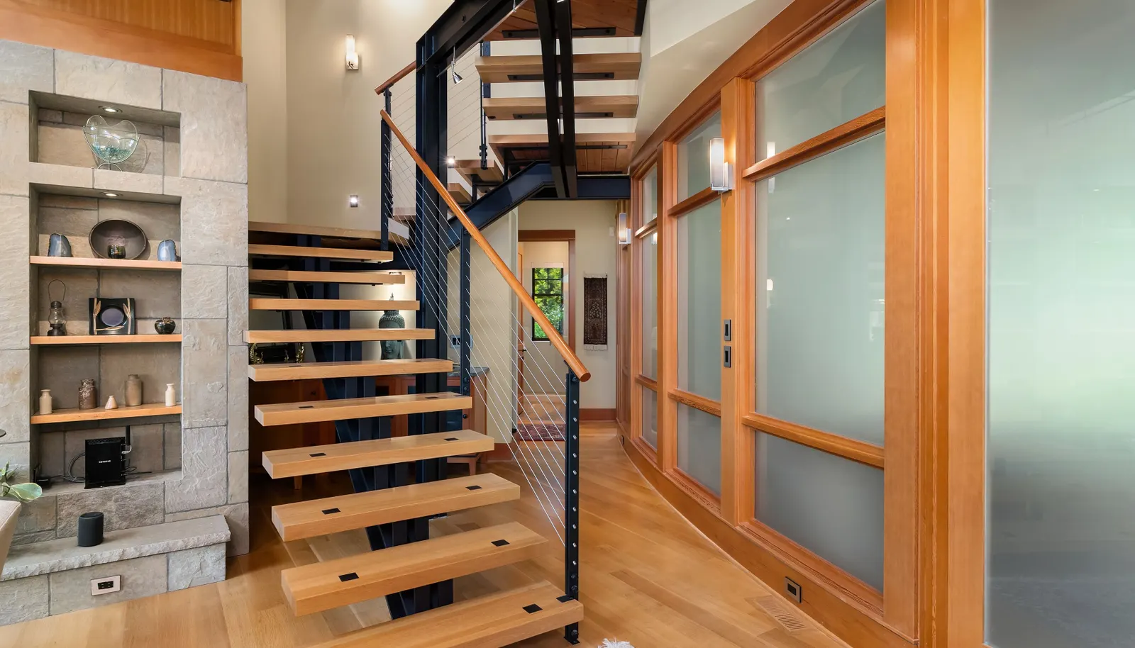 Steel beam construction is balanced with warm wood. A timeless architectural balance. The cozy den/TV room is behind the frosted glass curved wall