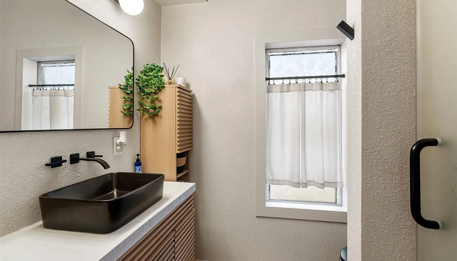 The updated bathroom makes a memorable statement with a shower wrapped in textured concrete walls