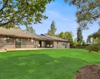 This is a view of the backyard showing a large lawn (it is now seasonally brown). The backyard is fenced. This is a view of the backyard showing a large lawn (it is now seasonally brown). The backyard is fenced.