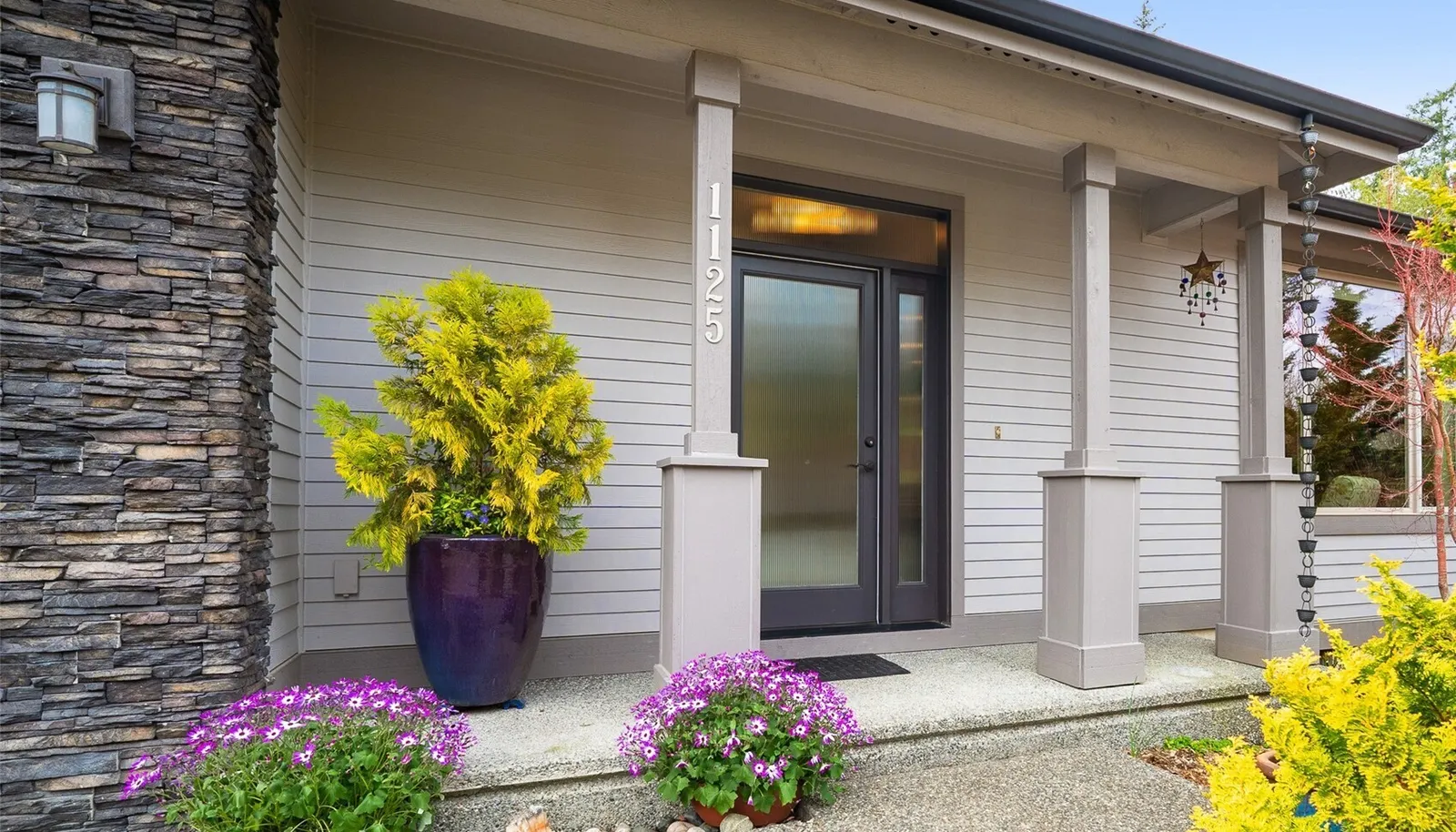 A covered entry creates a warm and inviting arrival, framed by simple architectural details and curated plantings.