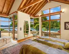 Looking from the primary suite out to the covered patio, outdoor fireplace and the water view that never gets old. The hot tub is to the right. 