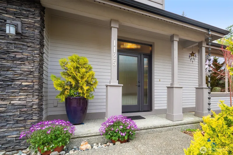 A covered entry creates a warm and inviting arrival, framed by simple architectural details and curated plantings.