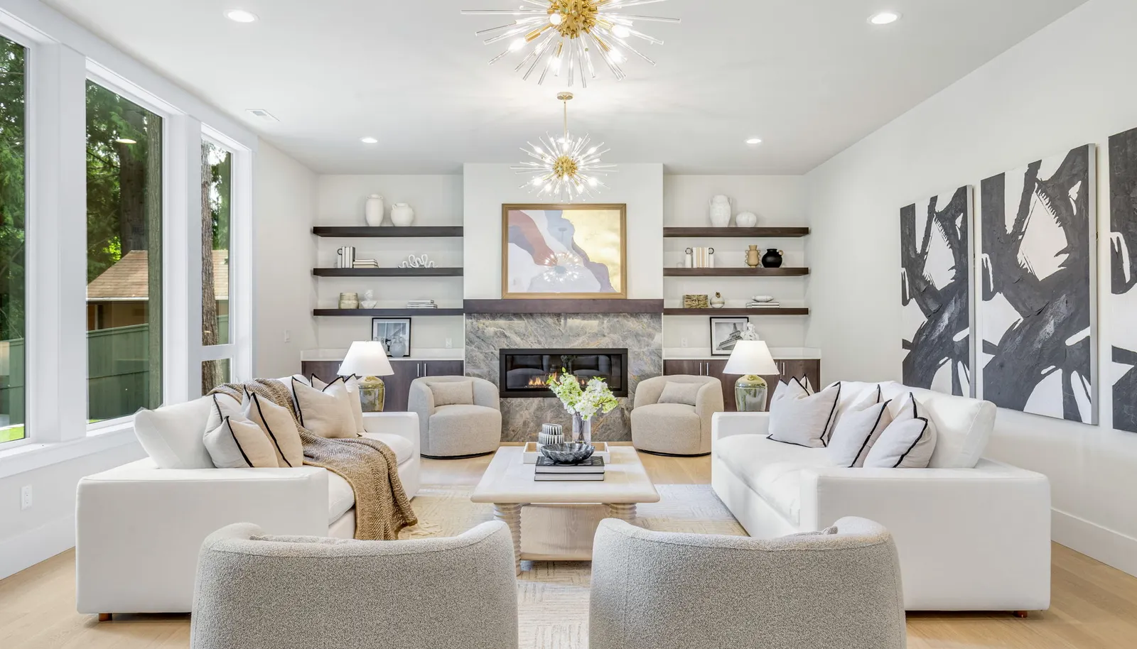 Custom built-in shelves and cabinets, dual chandeliers, and a modern fireplace with TV hookup.