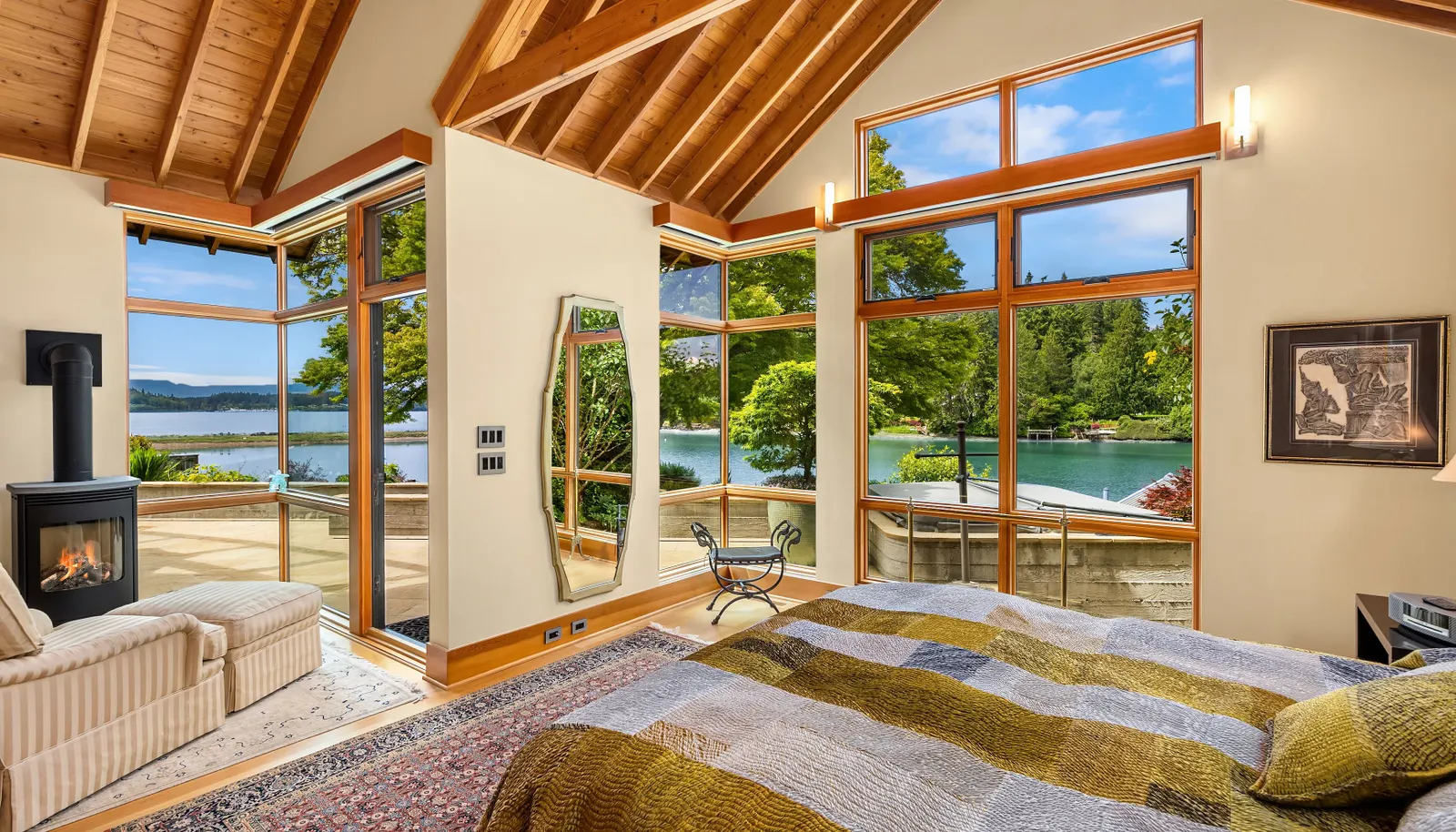 Looking from the primary suite out to the covered patio, outdoor fireplace and the water view that never gets old. The hot tub is to the right. 