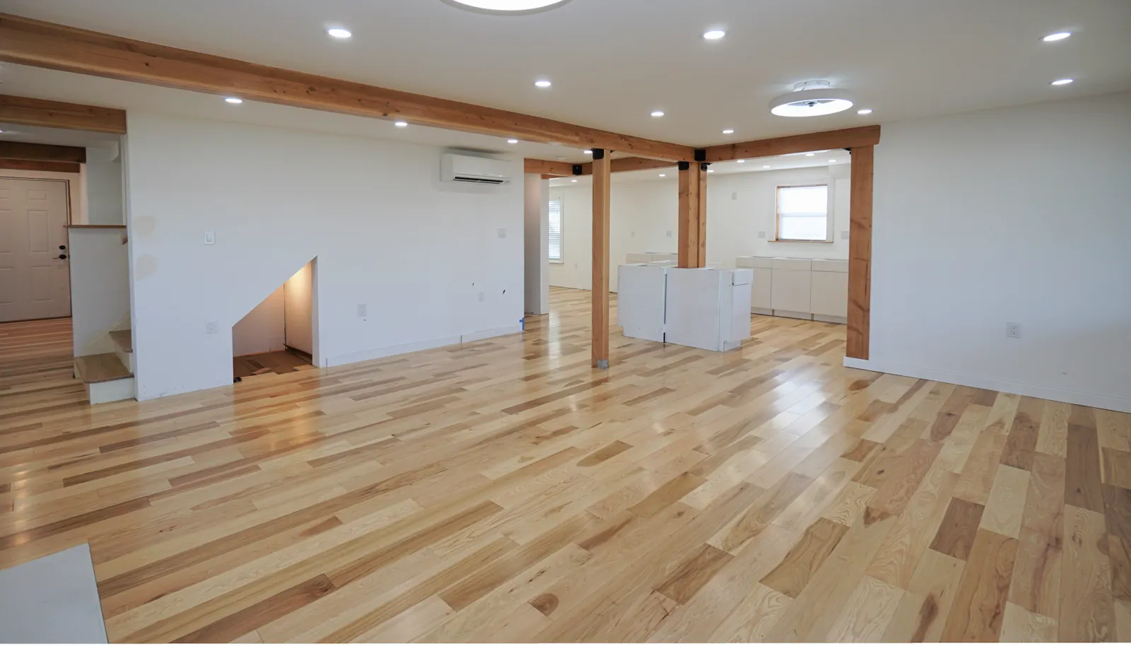 View from the waterside of the living room showing the back entry hallway and the stairway on the left. Ongoing kitchen installation and island cabinetry just to the right of center.