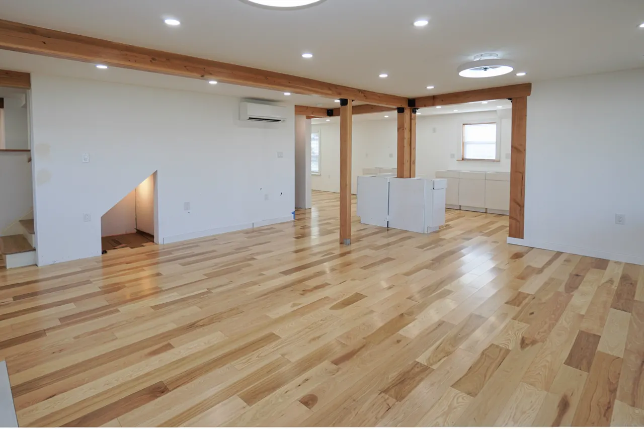 View from the waterside of the living room showing the back entry hallway and the stairway on the left. Ongoing kitchen installation and island cabinetry just to the right of center.