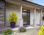 A covered entry creates a warm and inviting arrival, framed by simple architectural details and curated plantings.
